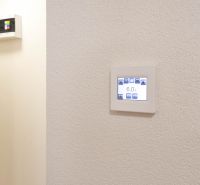 Adjustable thermostat on the wall in a studio apartment, simple design, white background.