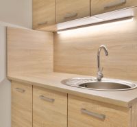 A kitchenette in a studio apartment with a wood decor and a sink.