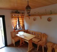 The rustic interior features a wooden bench and table, with furniture complementing the atmosphere of a family home.