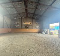 The interior of a building with a sand floor and a metal roof.