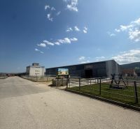 An industrial building in Hniezdne with a clear blue sky and an access road.