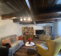 Living room in a family house with a wooden ceiling, comfortable seating, and decorative lighting.