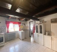 A kitchen in a family house with white cabinets, red curtains, and ceiling beams.