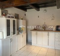 A kitchen in a family house with wooden beams and white cabinets.