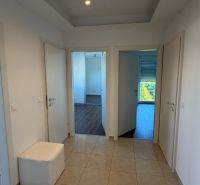 A hallway in a 3-room apartment with ceramic tiles and three white doors.