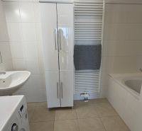 A bathroom in a 3-room apartment, with white furniture and a washing machine.