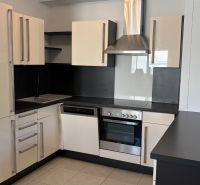 A kitchen in a 3-room apartment, with matching black and white kitchen cabinets and appliances.