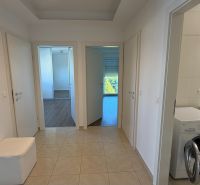 In the interior of a 3-room apartment with a wooden decor floor and a washing machine in the bathroom.