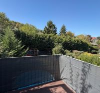 Terrace of a 3-room apartment in Wolfsthal with a view of greenery and blue sky.