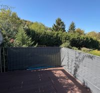 The balcony of a 3-room apartment in Wolfsthal with a view of greenery and a satellite dish.