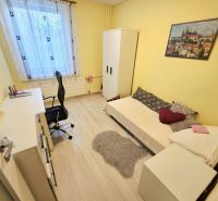 A yellow room with a single bed, a desk, and a wooden-patterned floor in a four-room apartment.