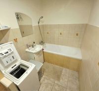 A bathroom with a stove washing machine, bathtub, and sink in a 4-room apartment.