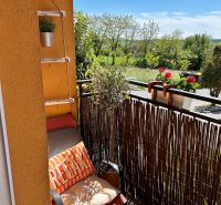 A balcony in a 3-room apartment with a comfortable chair and a view of greenery in Veľký Lapáš.