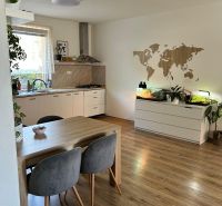 A kitchen in a 3-room apartment with a wooden decor floor, a table, and plants.