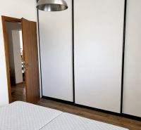 A bedroom in a 3-room apartment with a lamp, a wardrobe, and a wooden decor floor.