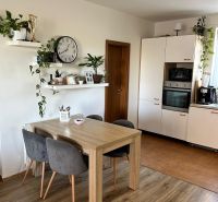 A kitchen in a 3-room apartment with wall shelves and a wooden decor floor.