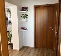 A hallway in a 3-room apartment with doors and flooring featuring a wood design.