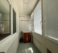 A glazed balcony with a wooden cabinet and a drying rack, part of a studio apartment.