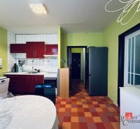 A kitchen in a studio apartment with colorful tiles, white tiles, and green walls.