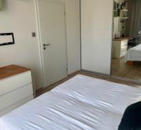 Bedroom in a 2-room apartment with a white bed and a wooden decor floor.