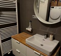 Bathroom with a sink and mirror in a 2-room apartment and a washing machine in the corner.
