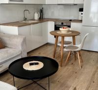 A kitchen corner with a round table and a floor with a wooden decor in a 2-room apartment.