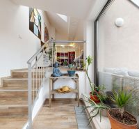 Stairs in a 4-room apartment with a decorative statue, a large window, and potted plants.