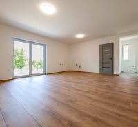 Living room in a family house with large windows and wooden decor flooring.