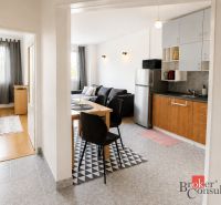 Interior of a 2-room apartment with a kitchen, living room, and wooden decor flooring.