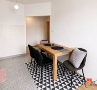 Dining area in a 2-room apartment with black chairs and a wooden table.
