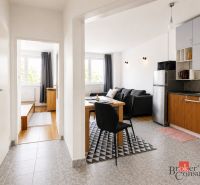 Interior of a 2-room apartment with a kitchen, dining table, and wooden decor flooring.