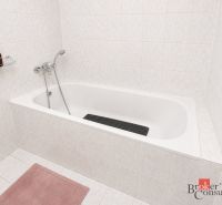 A bathroom with a bathtub tiled with white tiles in a 2-room apartment.