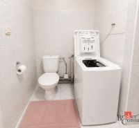 Bathroom in a 2-room apartment with a washing machine and toilet on the tiles.