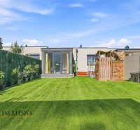 A garden of a family house in Oľdza with a lawn, a children's playground, and plants in pots.