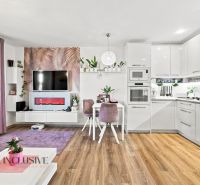Living room in a family house with a kitchen, white furniture, and a wooden decor floor.