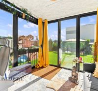 A sunny room in a family house with a view of the garden through glass doors.