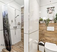 A bathroom in a family house with a wooden decor floor and a shower with a curtain.