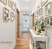 A hallway of a family house with a wooden decor floor and a lot of family photographs.