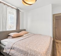 A bedroom in a family house with a wooden decor floor, a gray bed, and curtains.