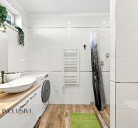 A bathroom in a family house with wooden floor decor and a washing machine.