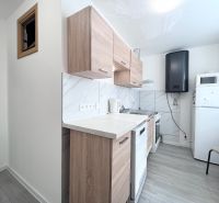A kitchen in a 3-room apartment with a wood-patterned floor and white appliances.