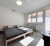 A bright bedroom with a bed, TV, and wooden decor flooring in a 3-room apartment.