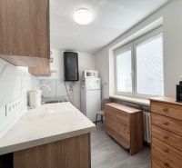 A kitchen in a 3-room apartment with tiles and wooden cabinets.