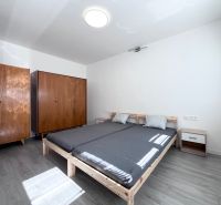 A bedroom with a bed, wooden wardrobes, and a floor with a wooden decor in a 3-room apartment.