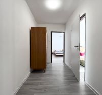 A hallway with a wooden decor floor in a 3-room apartment, a dark wardrobe, doors to the rooms.