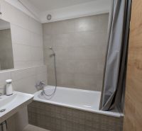A bathroom in light tones with a bathtub and a shower, ideal for a 2-room apartment.
