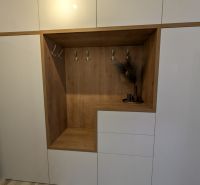 White built-in wardrobe with wood decor and hangers in a 2-room apartment.