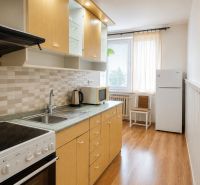 A kitchen in a 2-room apartment with a wooden decor floor and appliances.