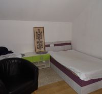 A room in a 2-room apartment with a bed, an armchair, and a floor with a wood decor.