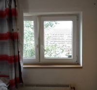 A window with a curtain and a view of the roof in a 2-room apartment.